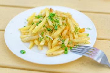 French fries on a plate on a yellow wooden background.