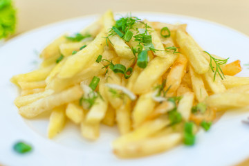 French fries on a plate on a yellow wooden background.