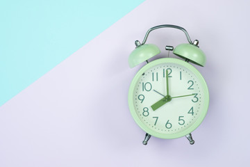 Vintage alarm clock on sweet pastel colored paper top view, background texture, pink, purple, yellow, beige, green and blue colour.