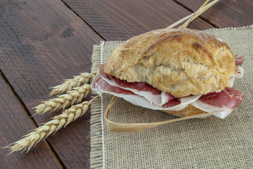 bocadillo de jamón iberico sobre arpillera y espigas de trigo 