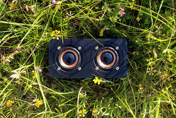 close-up of a portable audio speaker in the grass, freedom of listening music outdoors to relax and have fun