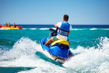 young adult man running the wave on jet ski during summer vacation