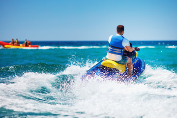 young adult man running the wave on jet ski during summer vacation