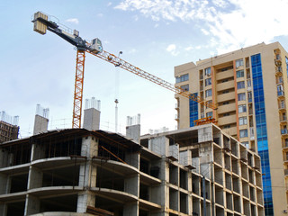 Construction crane near unfinished bulding against blue sky. Construction site.