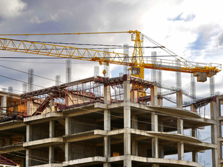 Fototapeta na wymiar Construction site background. Construction crane near unfinished building under cloudy sky.