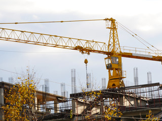 Huge crane near building under construction. Construction site in autumn