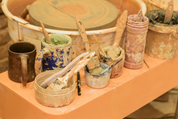 close up of dirty pottery wheel and colorful mud in jars after work