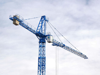 Industrial crane against cloudy sky. Construction site