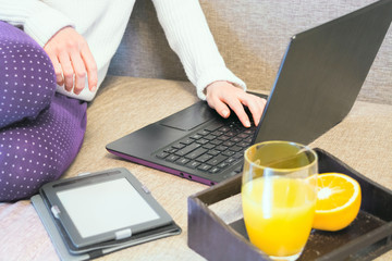 Working or studing at home concept, young woman in casual style with laptop, ebook and fresh orange...