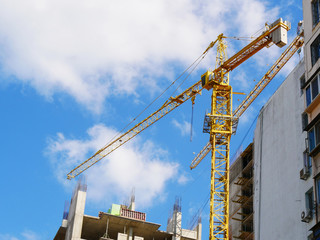 Construction cranes near building. Construction site against blue sky