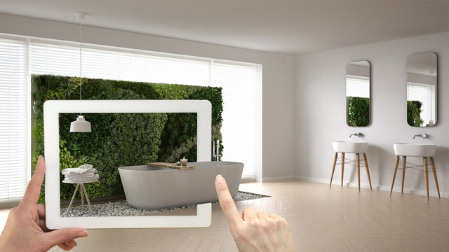 Augmented reality concept. Hand holding tablet with AR application used to simulate furniture and interior design products in real home, bathroom with vertical garden