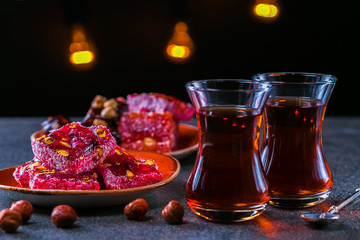 Turkish tea in traditional glass and plate with rahat lokum. Istanbul cafe with oriental culture of the street food.Evening time.