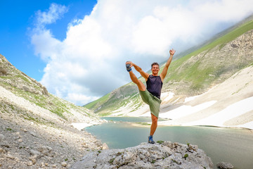 Man practice Yoga position over a big stone after a trekking to  high altitude lake (Pilato lake)  in the National Park of the Sibillini Mountains in Italy