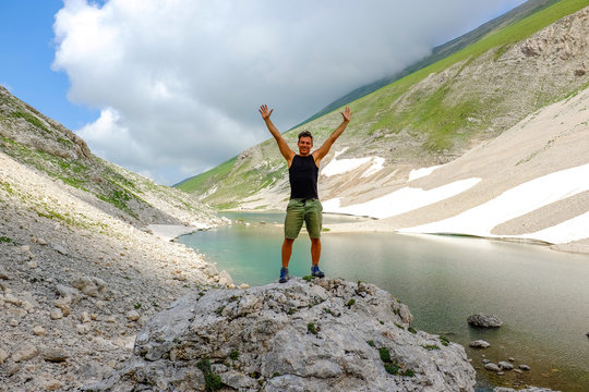 Man standing, after a trekking,  over  big stone in Pilato lake, Sibillini mountains, Marche Italy. Meditation and relaxation concept