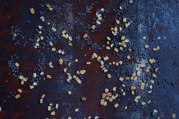 Black sesame seeds and cane sugar on dark concrete background. Food background. Copy space