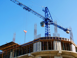 Crane near concrete building under construction. Construction site.