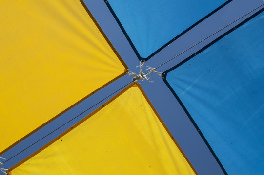 fondo con lona de dos colores/Toldos decorativos de dos colores amarillo y azul formando una x en verano en una calle de Madrid. Espa&ntilde;a