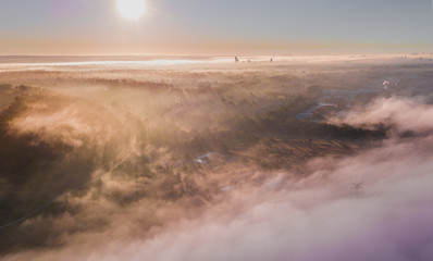 Fog and mist with the rays of sun shining through in the morning. Drone aerial shot over Western Sydney.