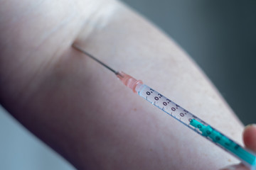 Syringe at the arm of a woman in the hospital