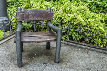 Silla en una plaza/sillón de madera para que se siente la gente en una plaza con jardín en Madrid. España
