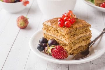 Honey cake with strawberries, mint and currant, a Cup of tea on a light background