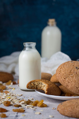 Healthy Breakfast with Oatmeal Cookies, Raisins, Oatmeal and Milk on a Dark Blue Background. Concept Healthy Eating