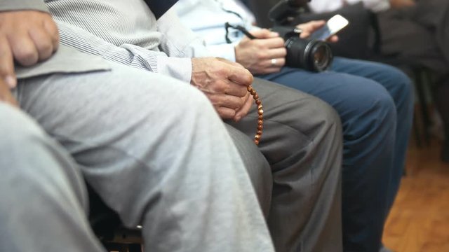 Male hand touches the rosary at the muslim conference