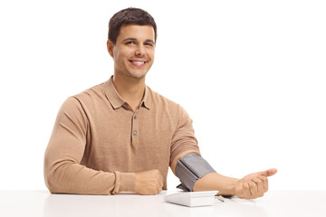 Young guy seated at a table measuring his blood pressure