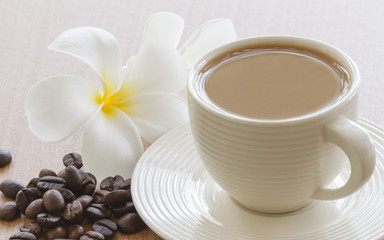 Cup Of Coffee With Frangipani (Plumeria) Flower And Roasted Coffee Beans On Table In Morning.