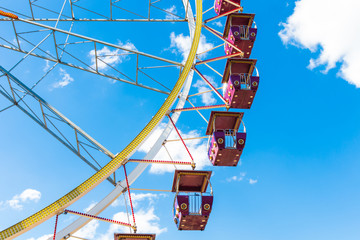 Ferris wheel against the blue sky. Empty red cabins close up