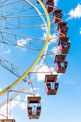 Ferris wheel against the blue sky. Empty red cabins close up