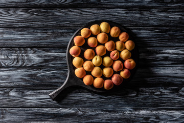 top view of pile of ripe apricots in tray on wooden table