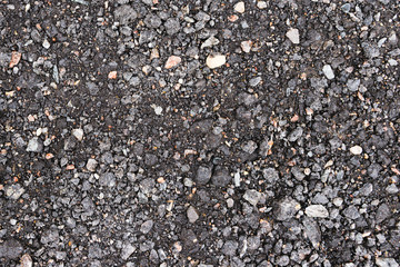 Black and gray asphalt with rocks background texture closup