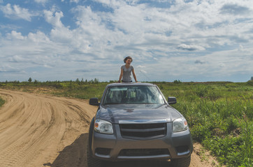 girl on an SUV in a field on a sandy road