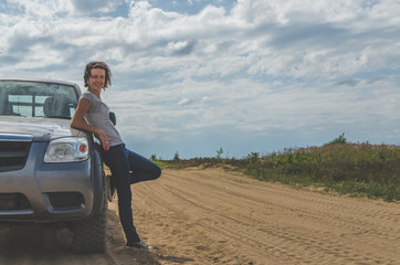 girl on an SUV in a field on a sandy road