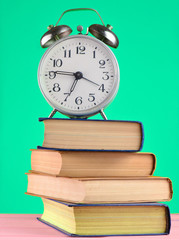 Alarm clock on top of piles of books