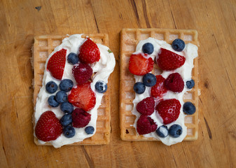 Selbstgemachte leckere Waffeln mit Erdbeeren, Blauberen und Sahne