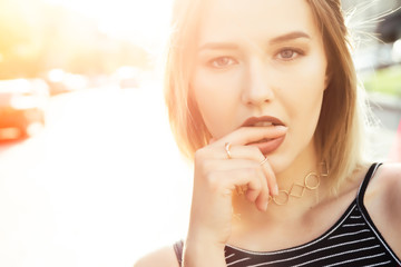 Naklejka premium Close-up portrait of seductive woman with finger on lips,outside.Natural light, backlight.