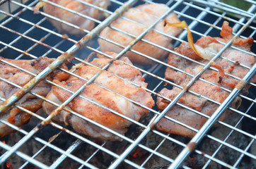 Preparation on bbq. Dish with roasted meat on abstract background. Hot tasty smokey barbecue meal at coals and burnt firewood. Cooking on fire outdoor. Nice smelling food. Fried chiken pieces