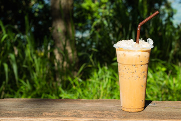 Iced coffee and a background of green trees.