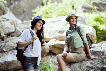 Two beautiful young girls travel in the mountains and enjoy the view of the landscape of stones.