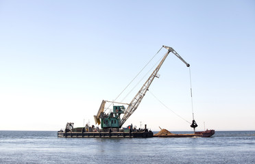 Fototapeta premium Плавучий кран загружает баржу