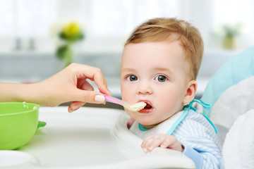 Mom feeds the child with a spoon with a porridge