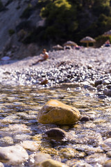 sunset at the beach. water covering the rocks on the shore. People on the background. Summer, holidays. Ibiza