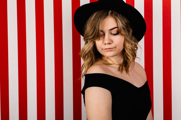 Pretty blond girl in the black hat on the studio