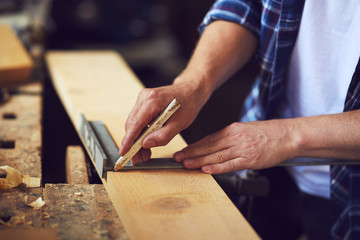 A carpenter uses a framing square in a carpentry shop.