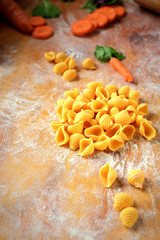 fresh homemade conchiglie pasta with carrots on a wooden table
