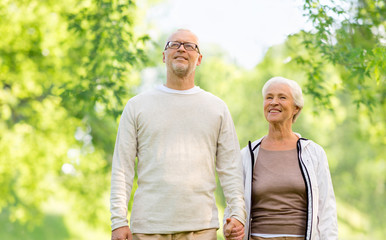 old age and people concept - happy senior couple holding hands over green natural background