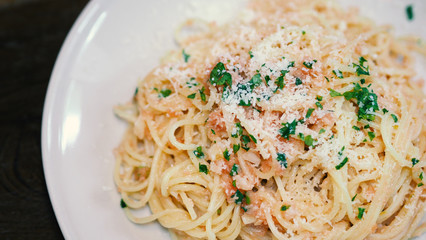Close-up image of spaghetti sauce tarako which made from fresh cod fish in Japan and mixed with Thai coriander on the top of white plate and famous italian-japanese menu dish in Thailand restaurant