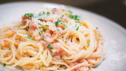 Close-up image of spaghetti sauce tarako which made from fresh cod fish in Japan and mixed with Thai coriander on the top of white plate and famous italian-japanese menu dish in Thailand restaurant